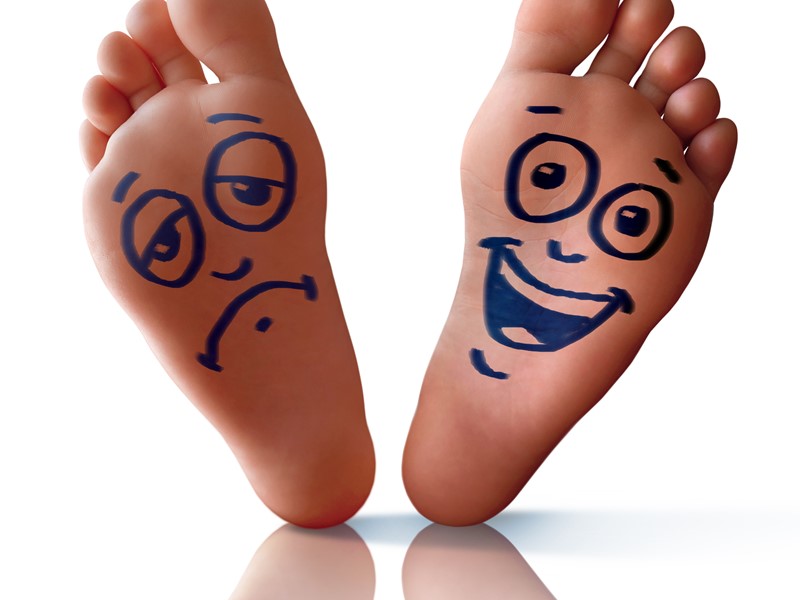 Happy and sad faces drawn on the soles of someone's feet