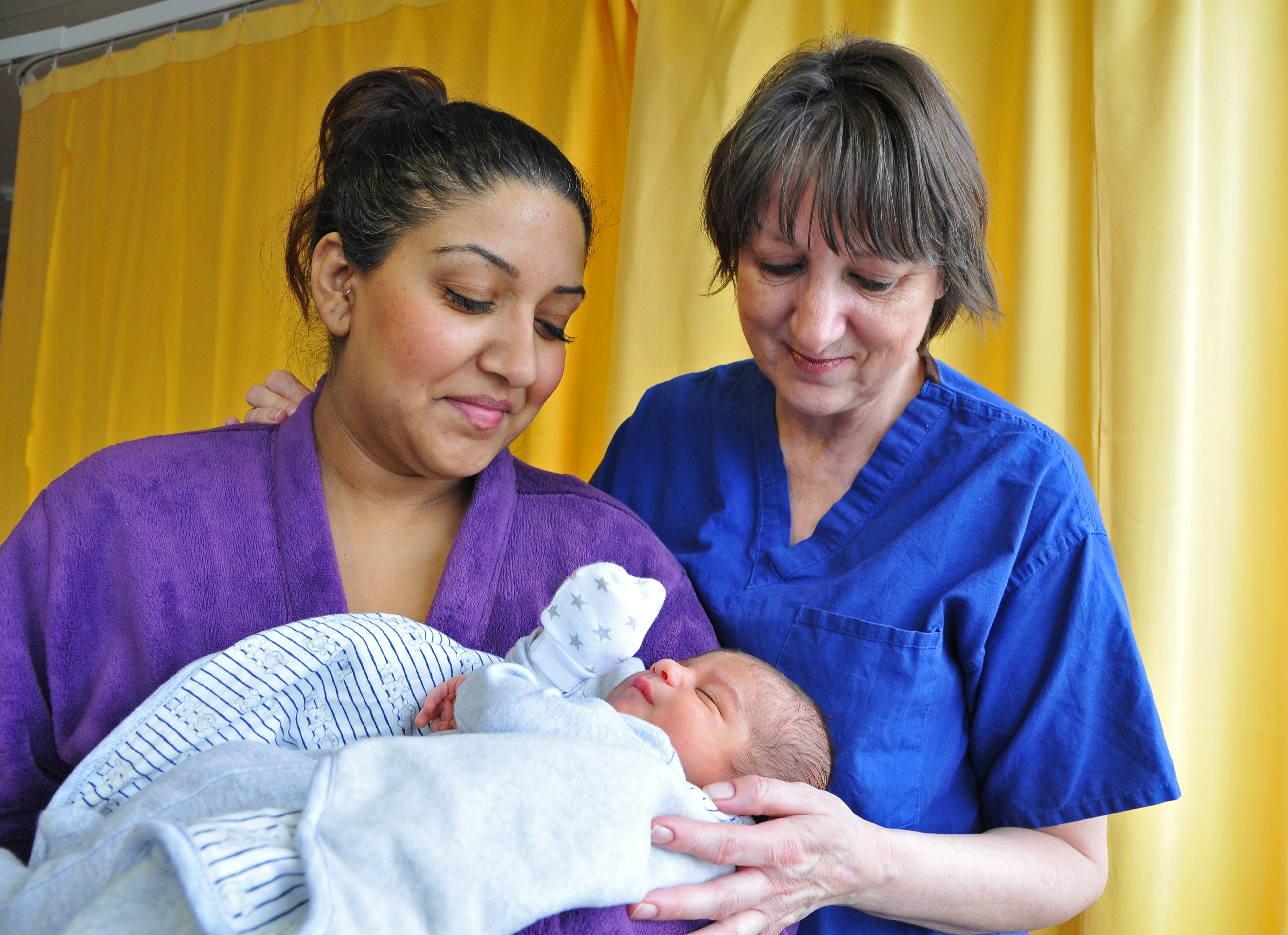 Mother holding baby in arms with nurse