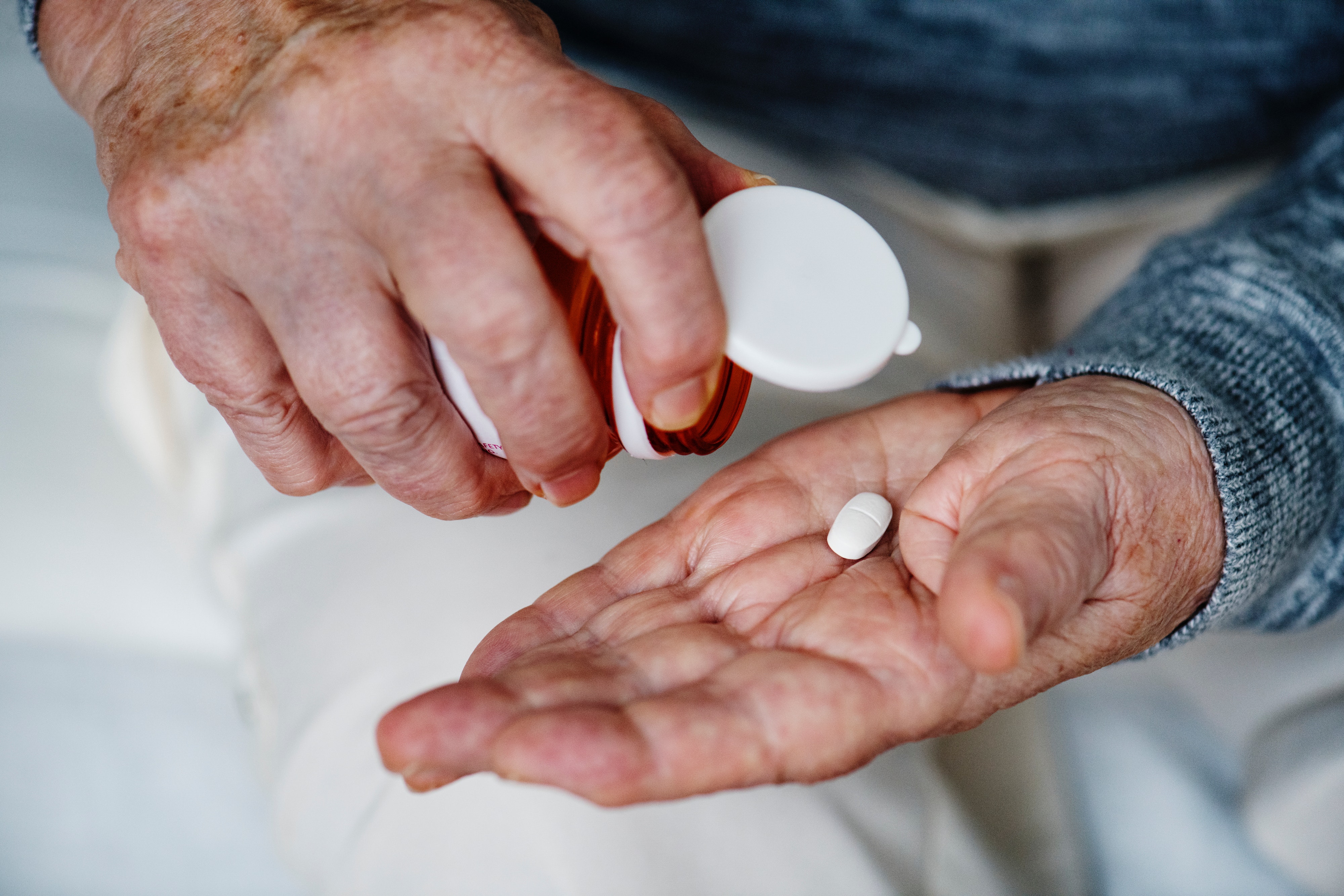 Person taking a tablet out of prescription bottle