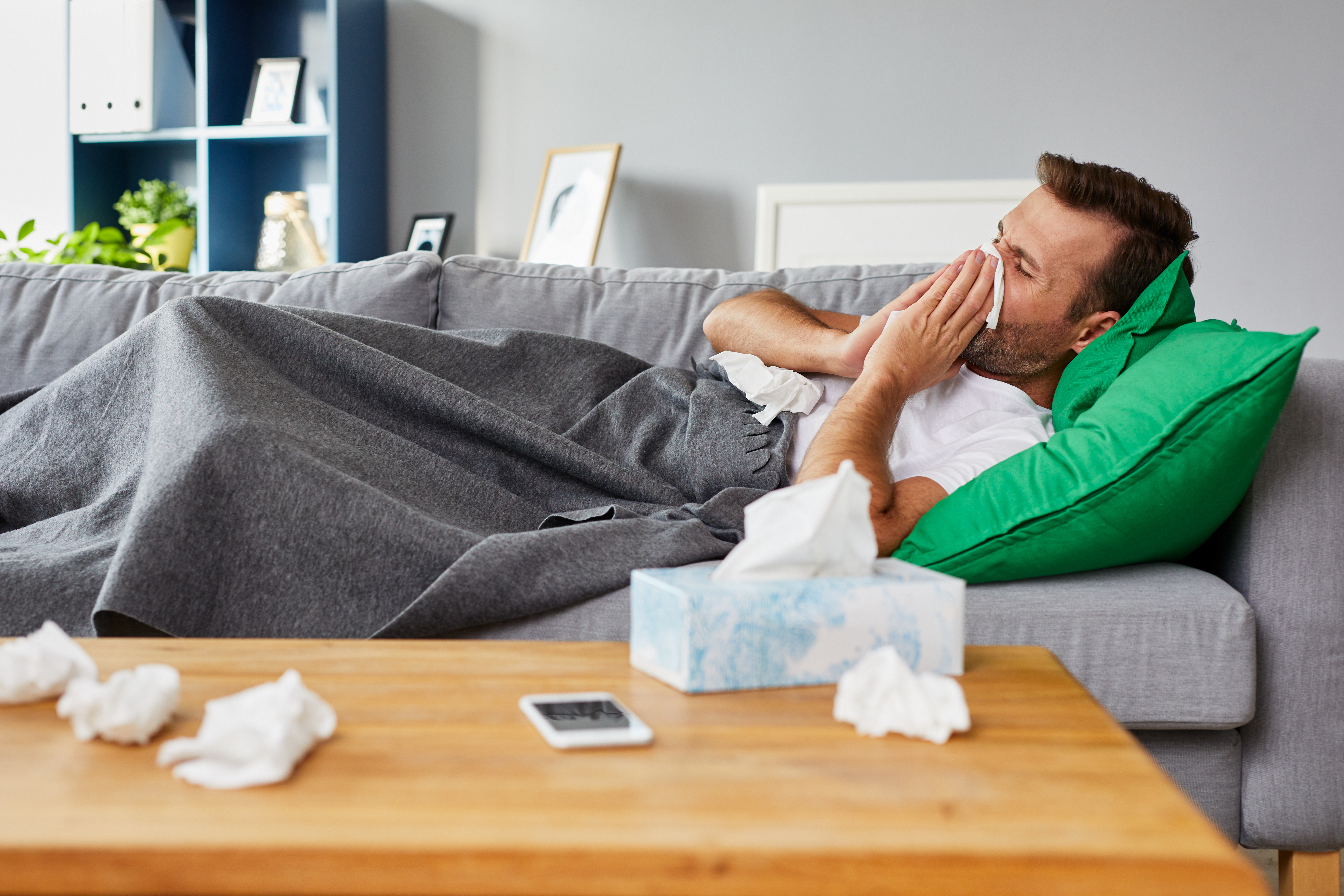 Man lying on couch looking unwell