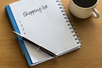 Shopping list written on notebook with cup of coffee